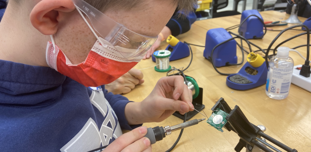 Kid soldering wire to a circuit board